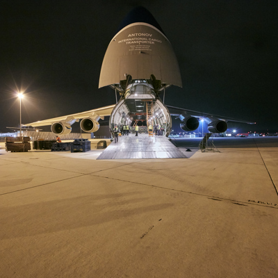 Frachtflugzeug wird bei Nacht durch die Ladeluke in der Nase beladen