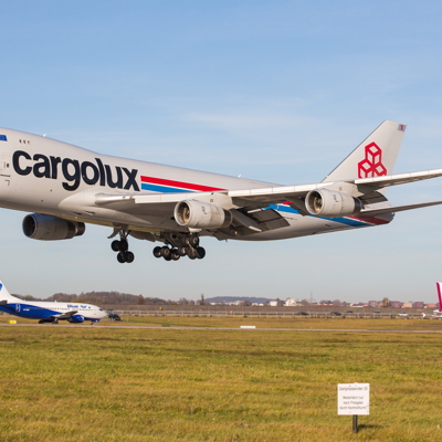 Frachtmaschine landet auf der Landebahn, im Hintergrund wartende Flugzeuge